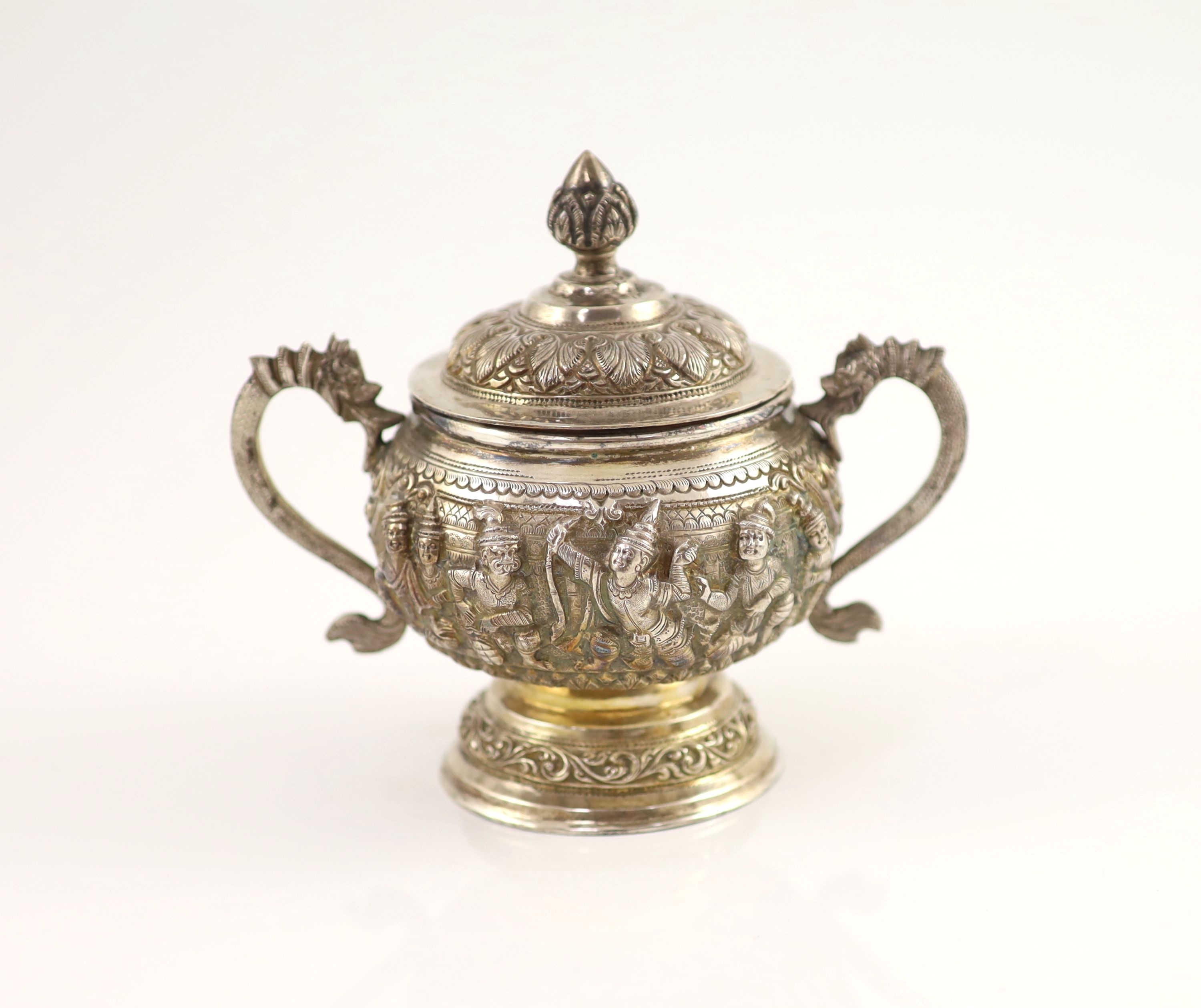 An impressive Burmese Sterling silver (950) three-piece tea service, with tray, cast with figures, teapot with cockerel spout and figural handle